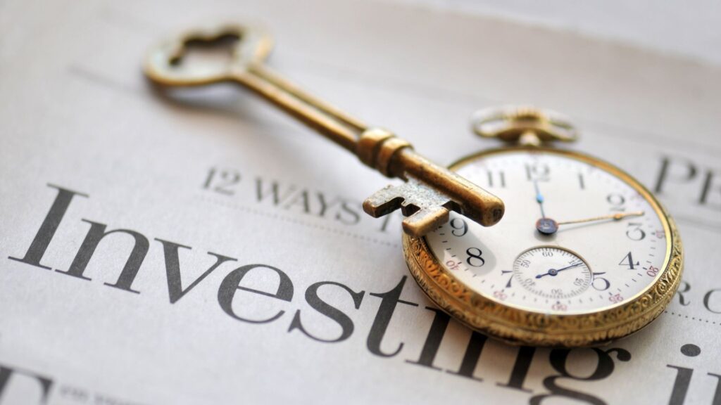 A vintage clock and key resting on a newspaper with the word “Invest,” representing the importance of time in investing.