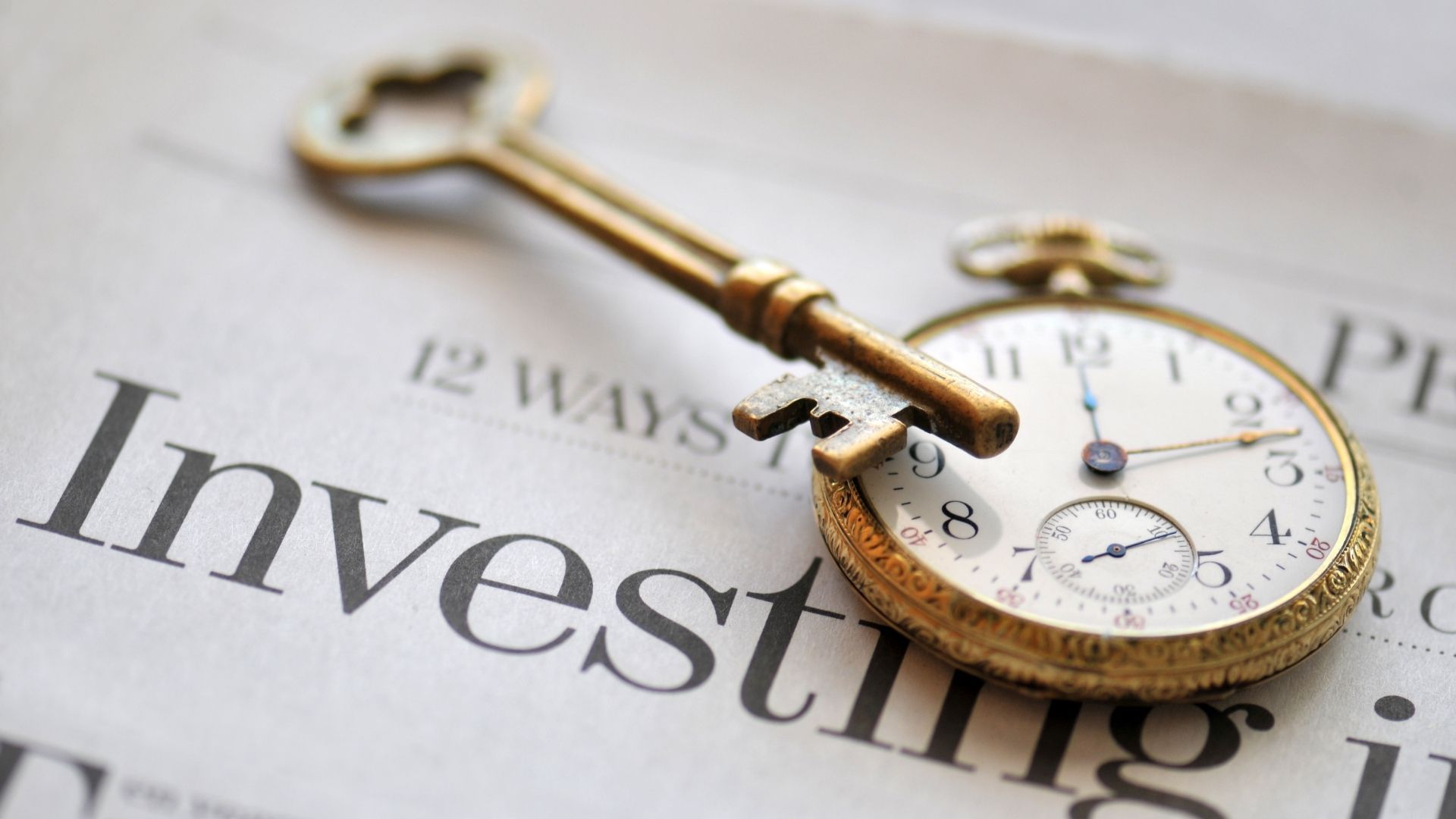 A vintage clock and key resting on a newspaper with the word “Invest,” representing the importance of time in investing.