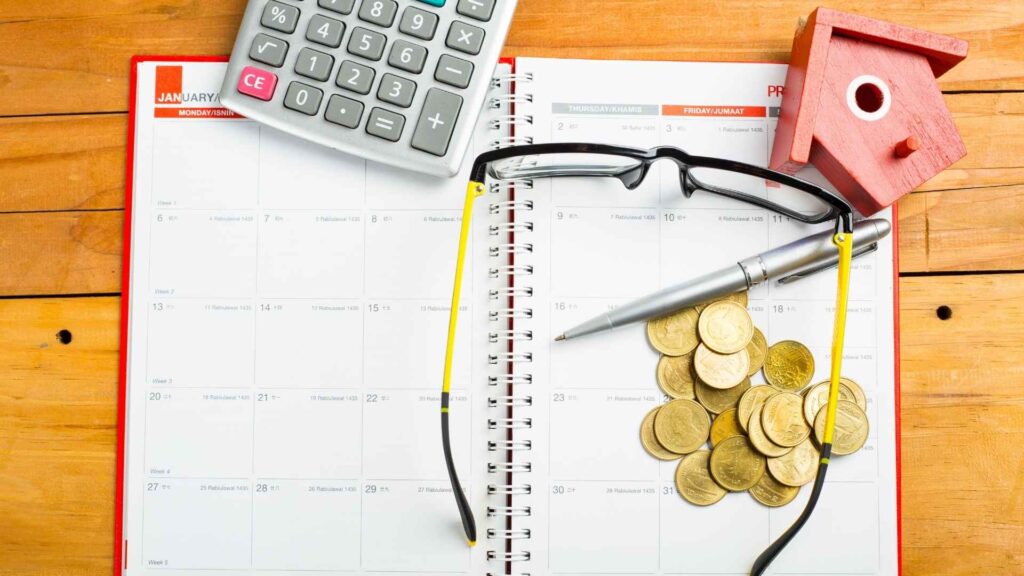 Kennedy Kha Phan – Financial Planning and Market Awareness – Newsletter Subscription Page A planner with coins, calculator, glasses, and a small house model, representing financial planning and market awareness.