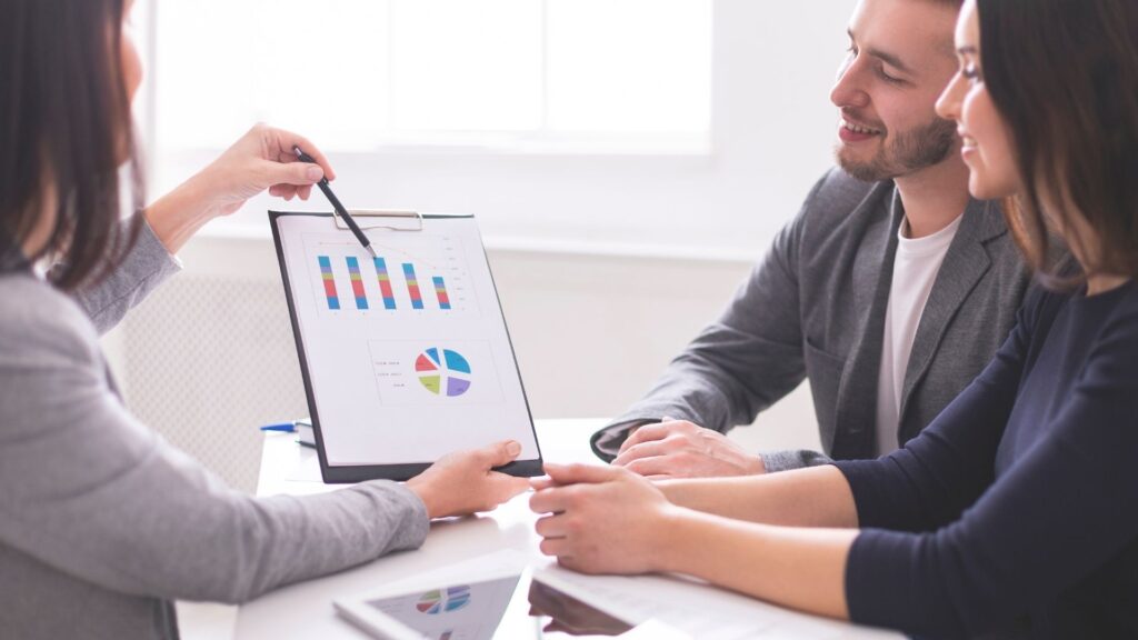 Nhóm người đang xem và thảo luận biểu đồ tài chính, thể hiện việc phân tích dữ liệu và trao đổi thông tin.