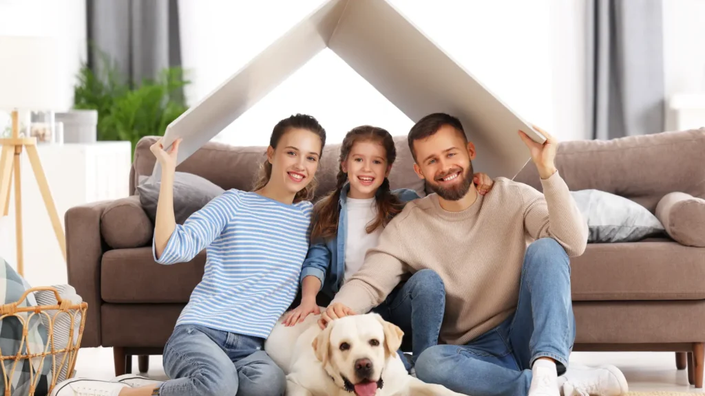 Một gia đình ngồi cùng nhau trong nhà, cùng che một mái nhà tượng trưng cho sự bảo vệ, ổn định và lập kế hoạch cho gia đình.