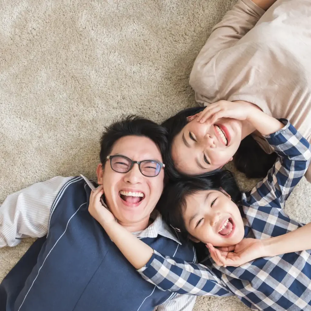 Kennedy Kha Phan – Gia Đình và Mục Tiêu Tài Chính Dài Hạn Một gia đình nằm cạnh nhau và mỉm cười, thể hiện các ưu tiên gia đình và mục tiêu tài chính dài hạn.