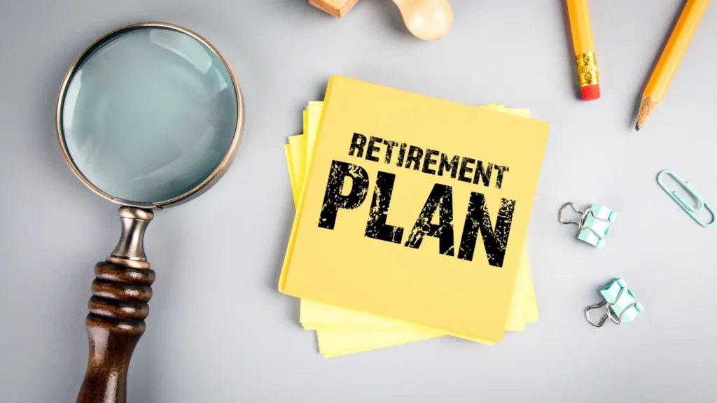 Retirement plan note on a desk with a magnifying glass, pencils, and office supplies, representing the importance of reviewing and preparing a clear retirement strategy.