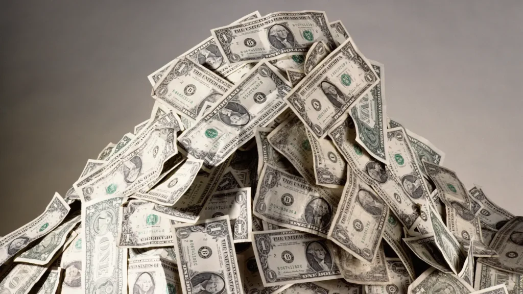 Pile of U.S. dollar bills representing cash savings, holding too much cash, opportunity cost, inflation risk, and personal finance planning.