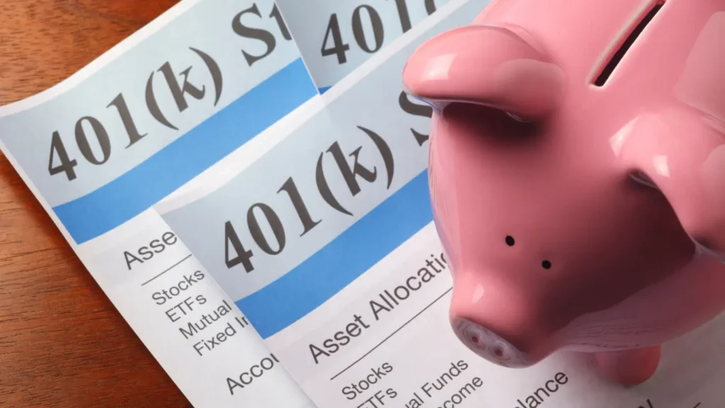 Piggy bank placed over 401(k) account documents showing retirement savings and investment allocation.